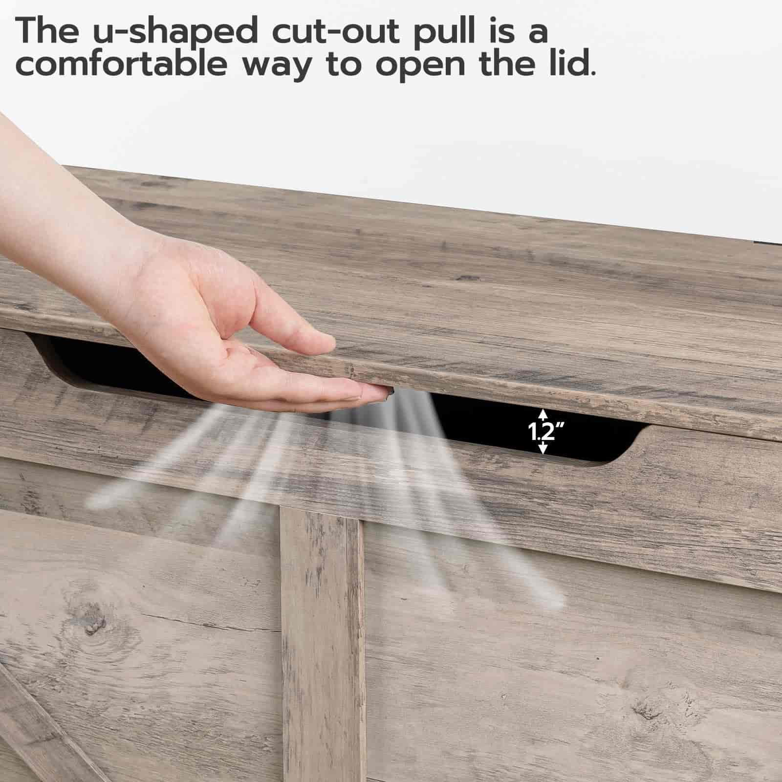 Wooden drawer with a hand using a u-shaped cut-out pull to open the lid.