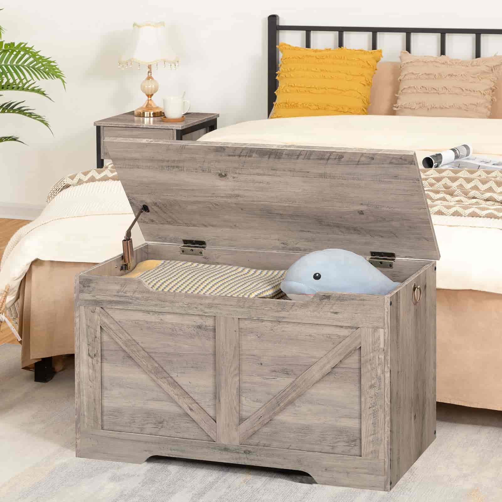 Wooden storage chest in a bedroom with a bed and pillows in the background