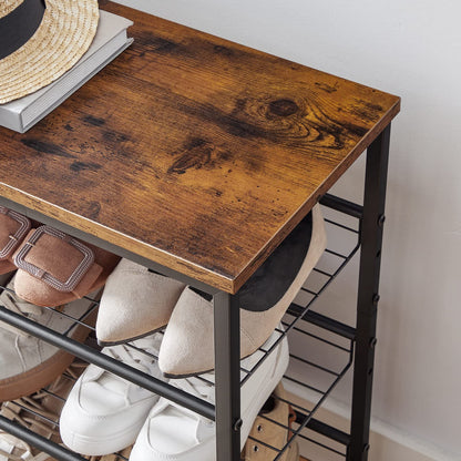 Wooden table with shoe rack underneath holding various shoes.