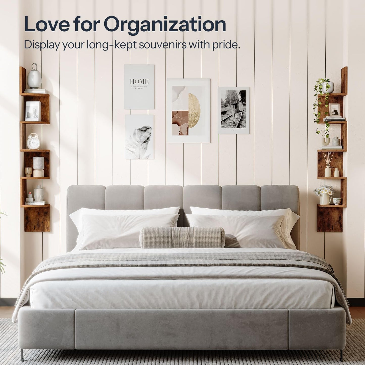 Gray upholstered bed with white bedding in a room with wooden shelves and framed pictures on the wall.