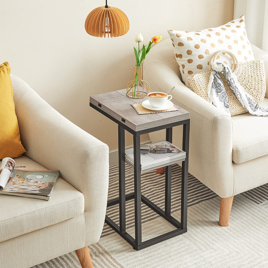 Small side table with a cup of coffee and flowers between two beige armchairs in a living room.