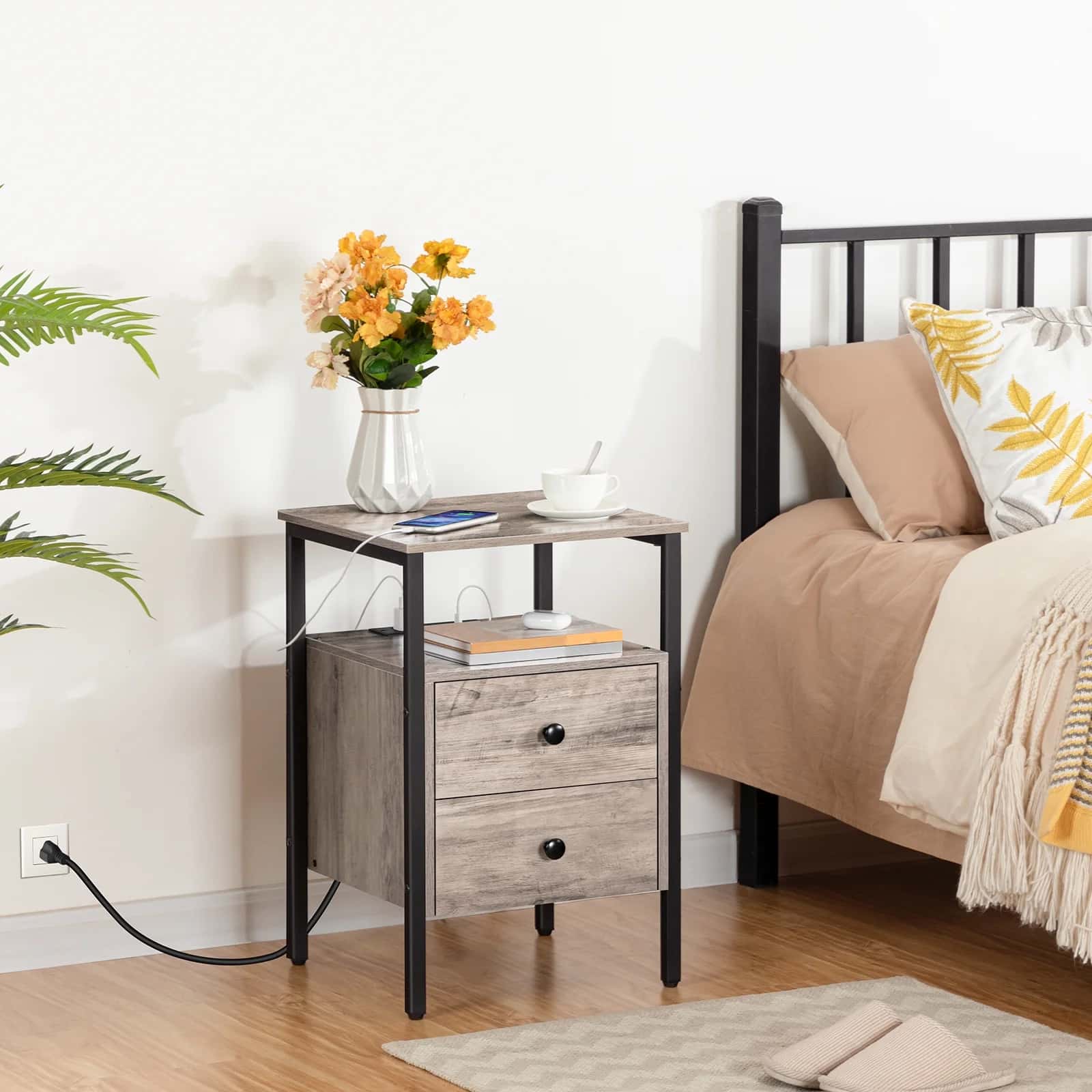 Nightstand with floral arrangement next to a bed in a bedroom setting