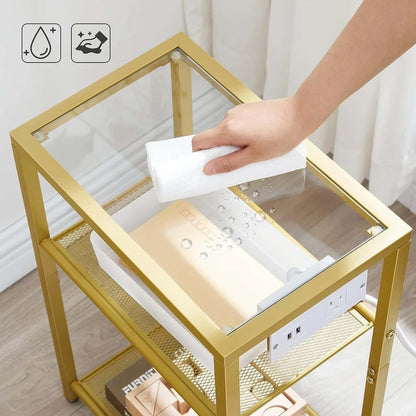 Person cleaning a glass-top gold metal table with a white cloth.