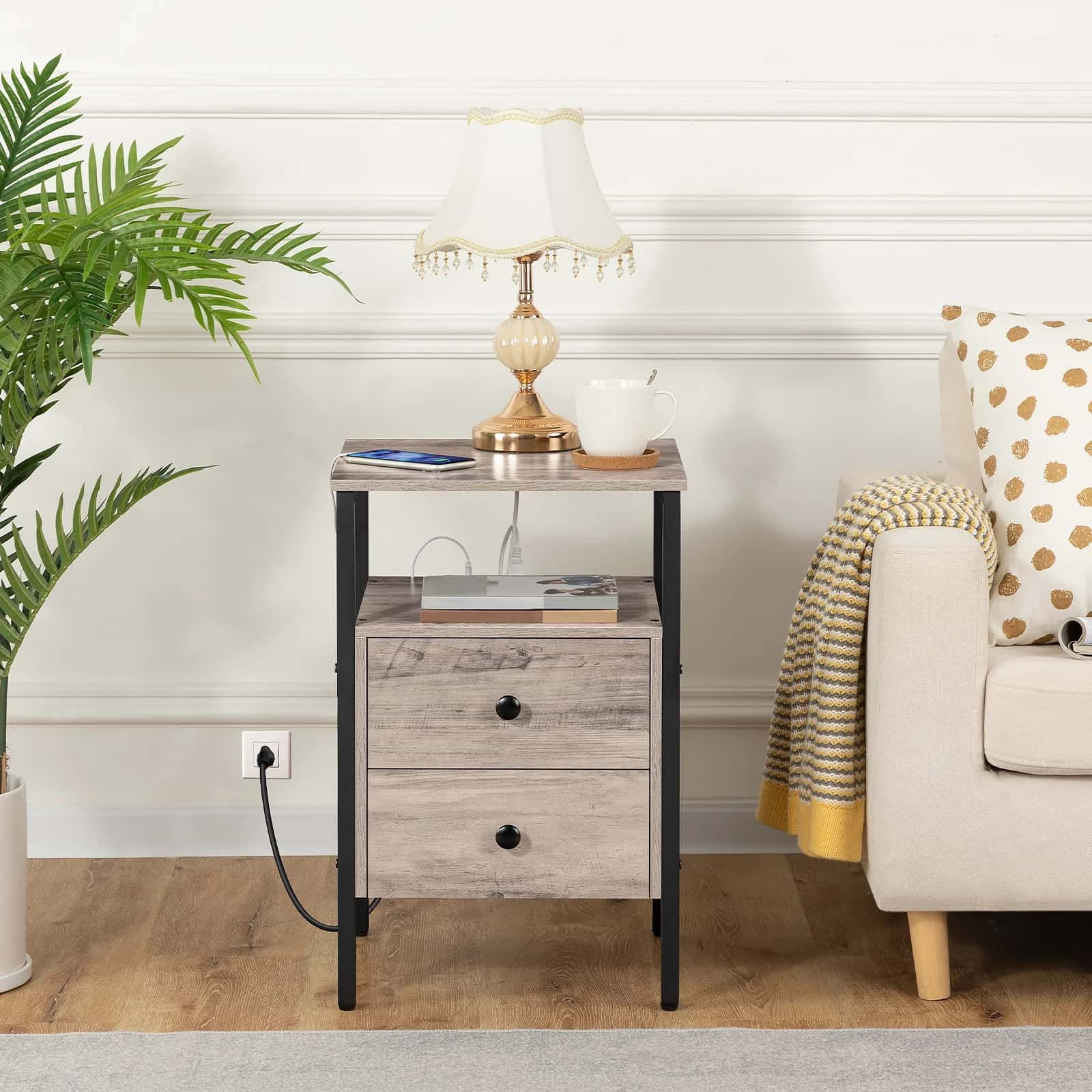 Side table with lamp and books next to a sofa with a polka dot pillow in a living room setting.