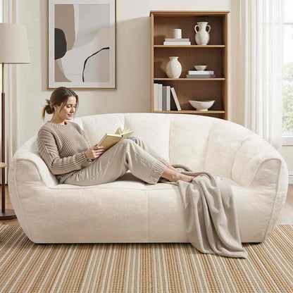 Woman reading a book on a white sofa in a cozy living room.