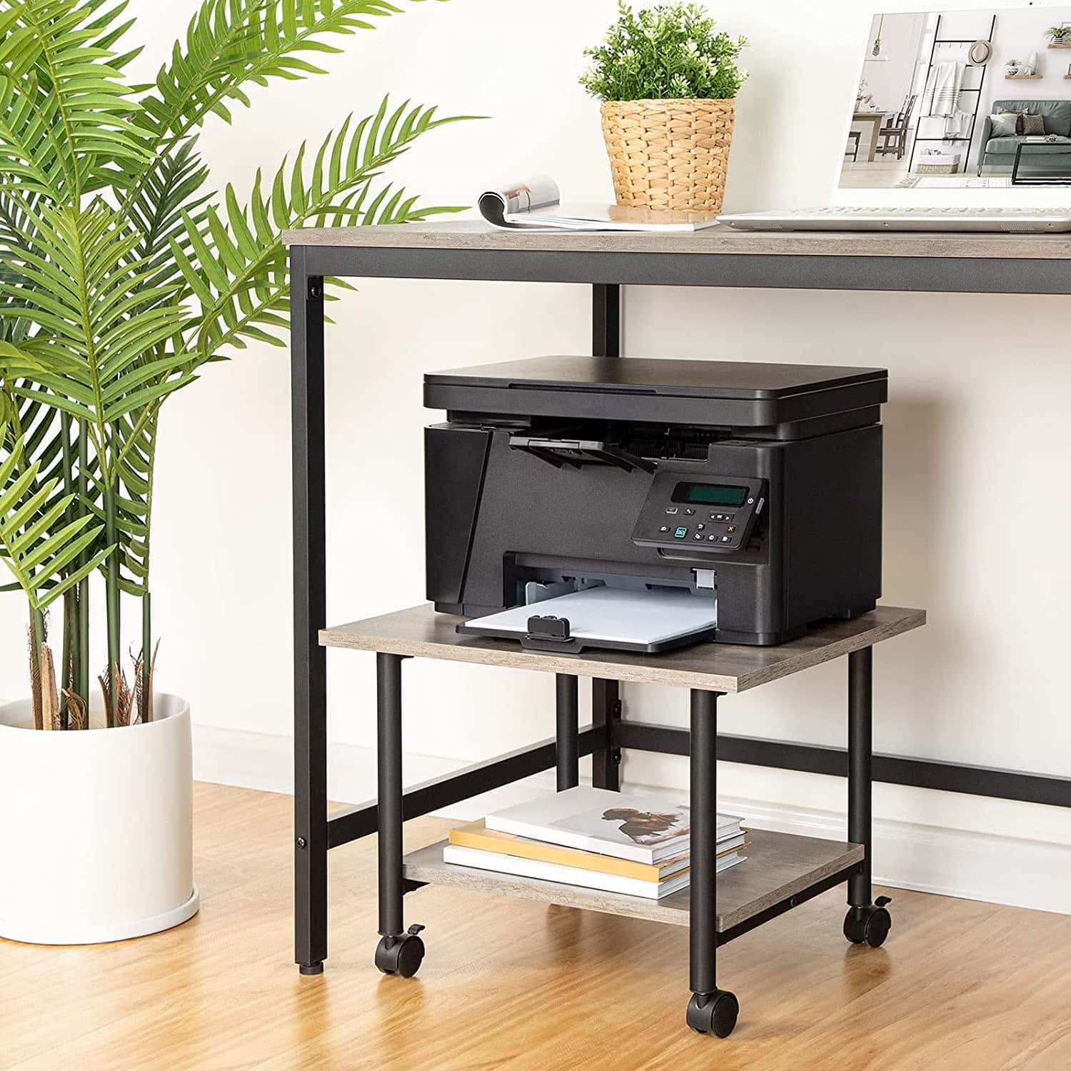 Black printer on a rolling desk with a plant and books in the background