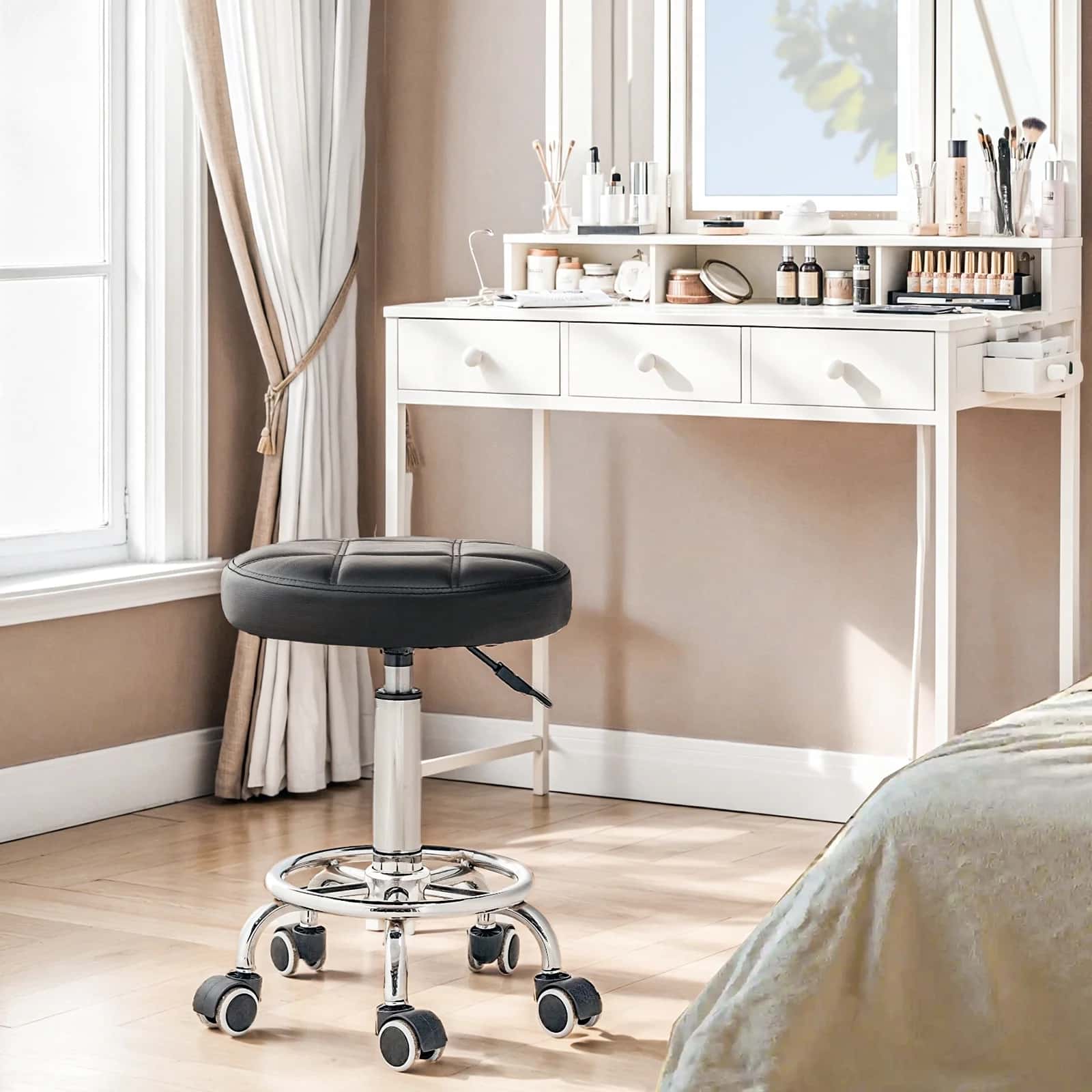 Black stool with wheels in a room with a white desk and window.