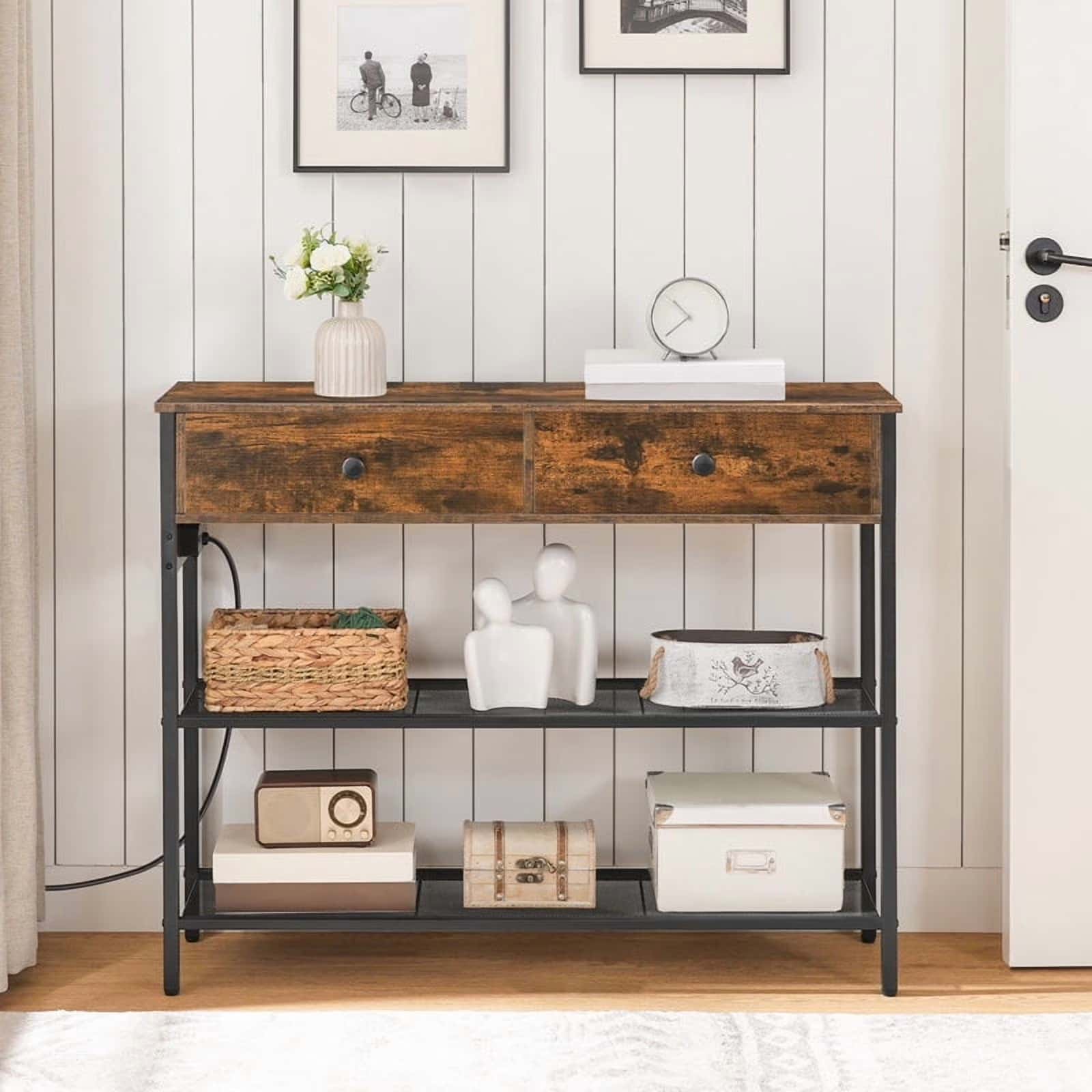 Wooden console table with decorative items against a white paneled wall.