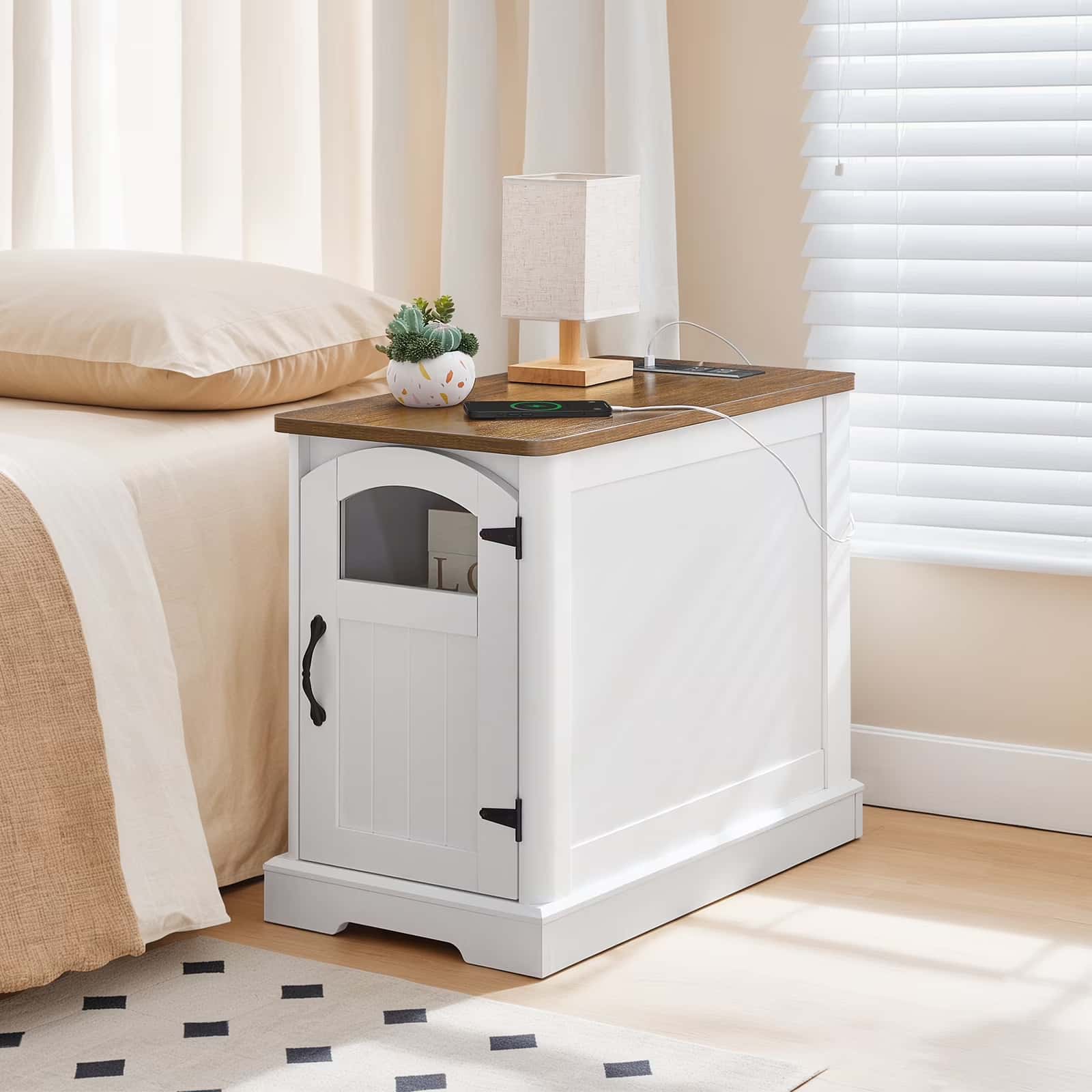 White nightstand with wooden top next to a bed in a bedroom.