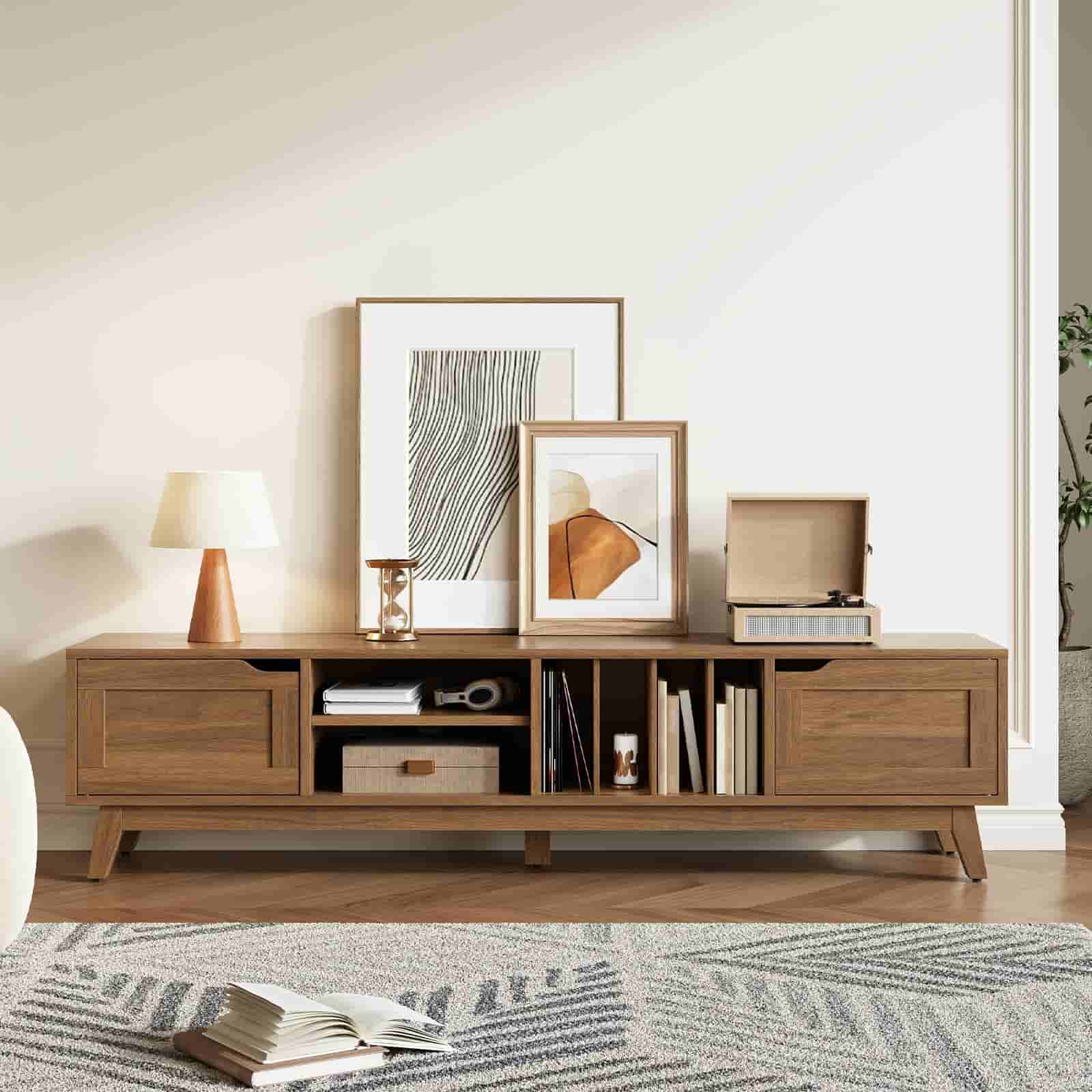 Wooden entertainment console with books, decor items, and framed pictures in a living room setting.
