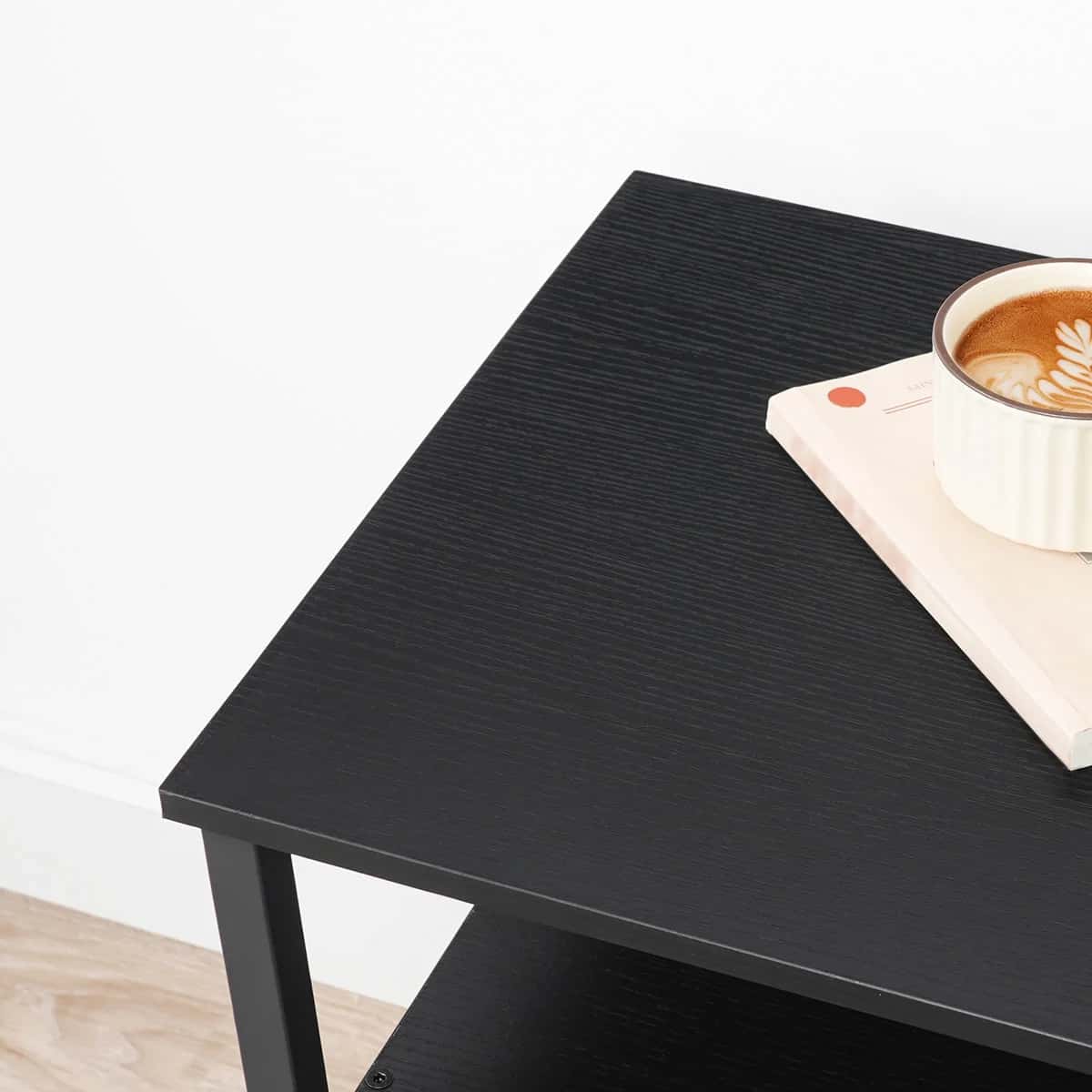 Black coffee table with a cup of coffee and a book on a white background