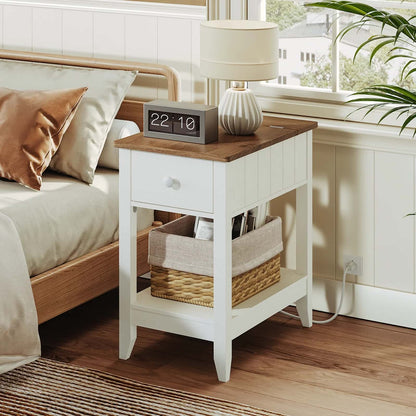 White nightstand with wooden top next to a bed in a bedroom.
