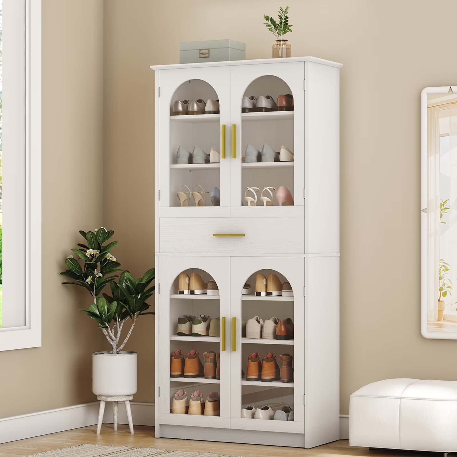 White cabinet with glass doors displaying various items in a room with a plant and ottoman.