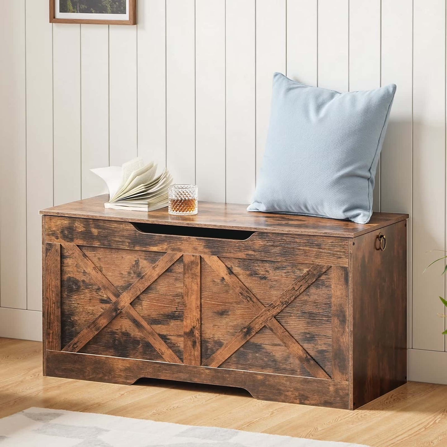 Wooden storage bench with a glass of whiskey and folded towels on a wooden floor.