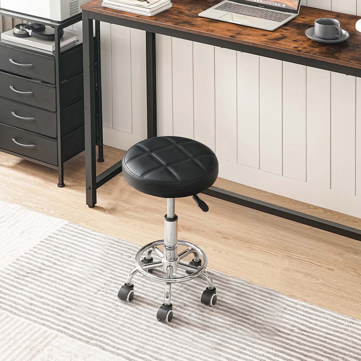 Black office stool in front of a wooden desk with a laptop and coffee cup.