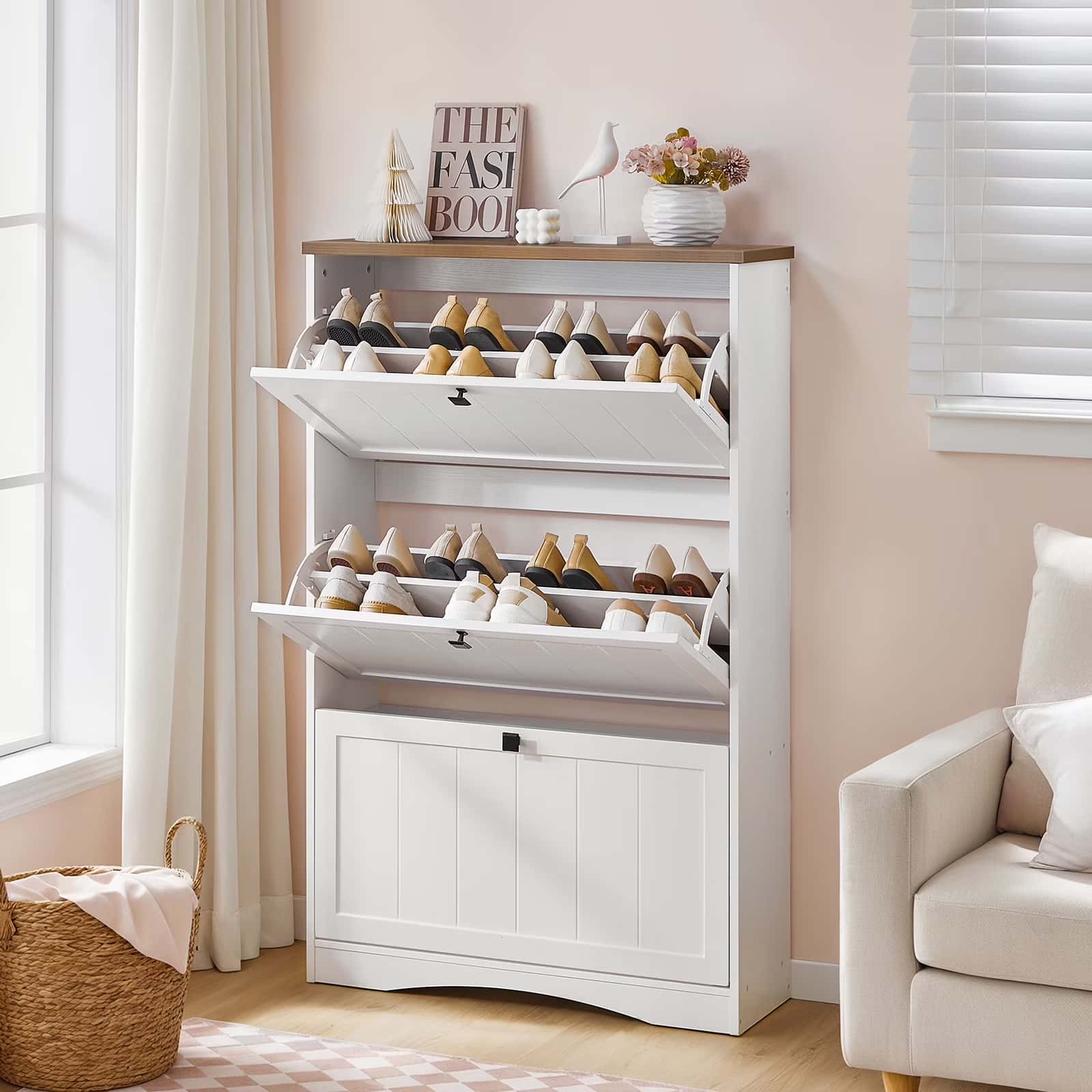 White shoe cabinet with open drawers filled with shoes in a room with a couch and window.