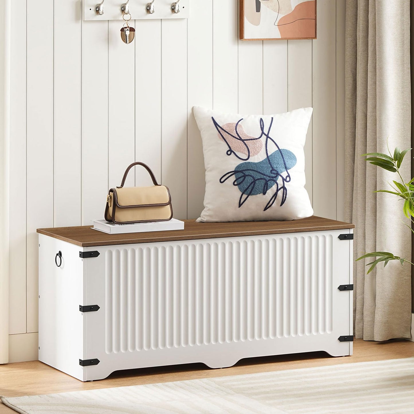 White storage bench with wooden top in a room setting with a pillow and handbag.
