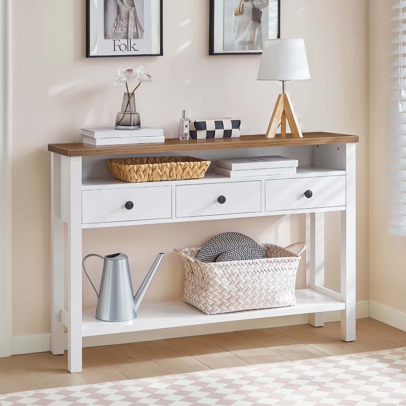 Console table with wooden top and white base, decorated with books, a basket, and a lamp.
