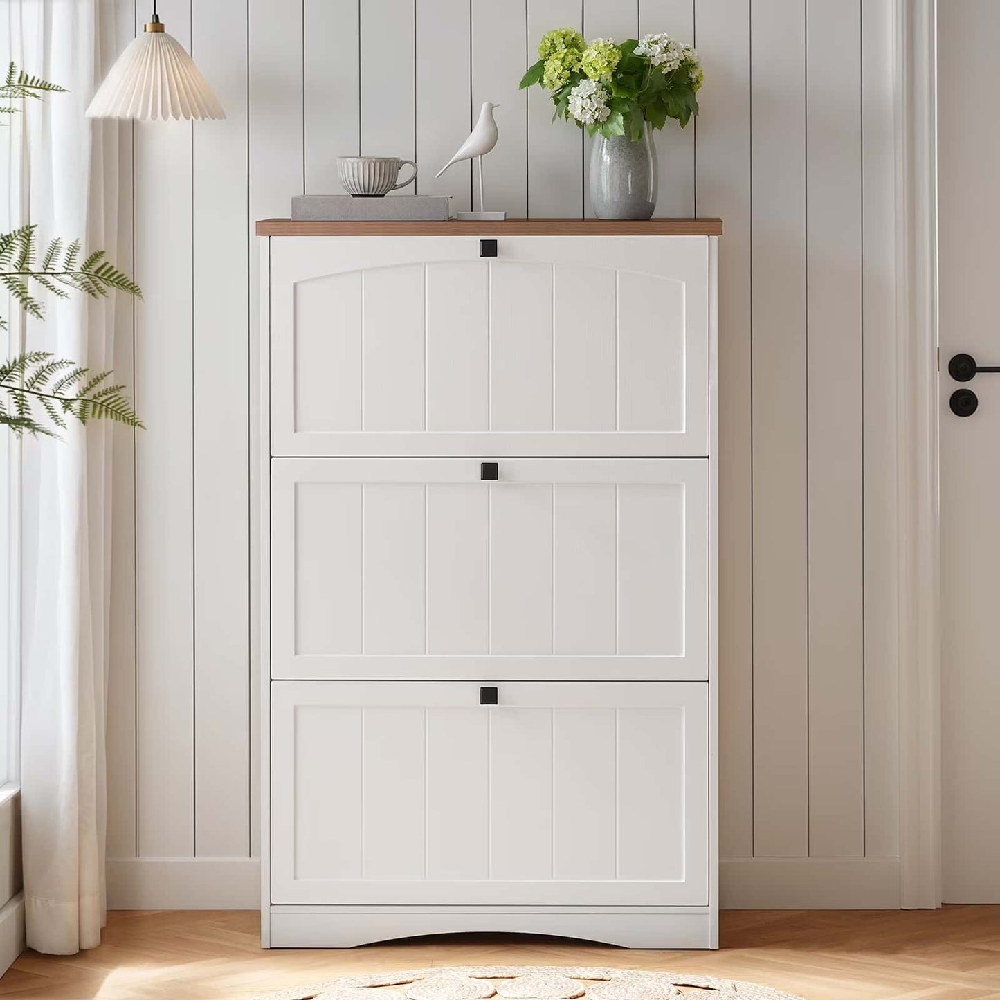 White shoe cabinet with wooden top in a room with plants and decor.