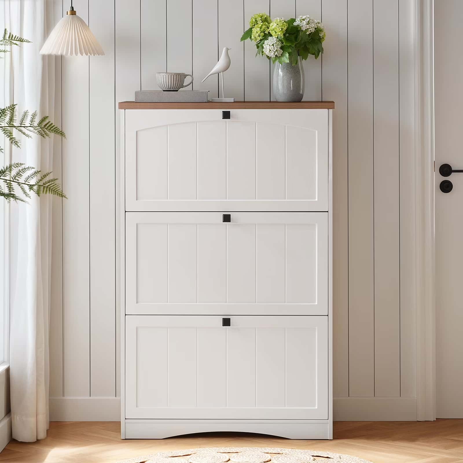 White shoe cabinet with wooden top in a room with plants and decor.
