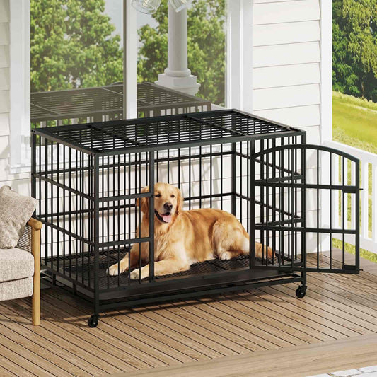 Dog in a large black metal crate on a wooden deck with a view of greenery and a house.