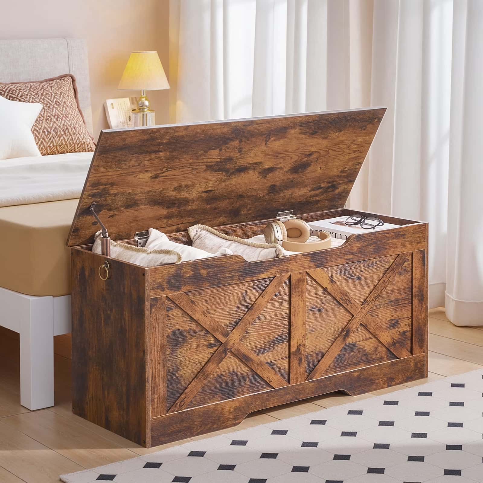 Wooden storage bench in a bedroom with a bed and lamp in the background.
