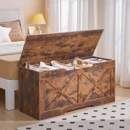 Wooden storage bench in a bedroom with a bed and lamp in the background.