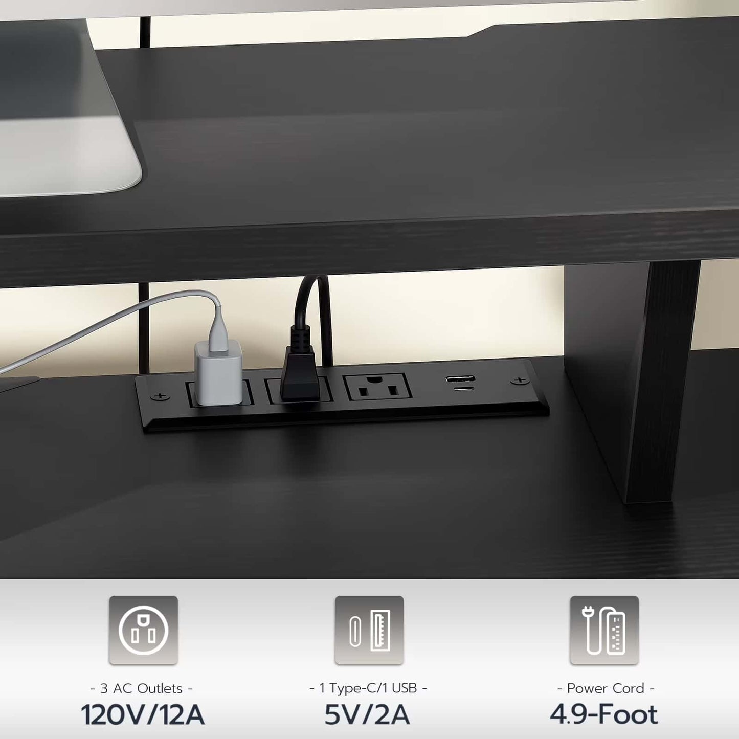 Black desk with power outlet panel underneath, showing electrical outlets and USB ports.
