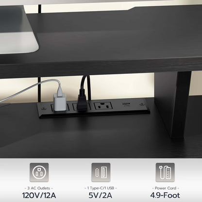 Black desk with power outlet panel underneath, showing electrical outlets and USB ports.