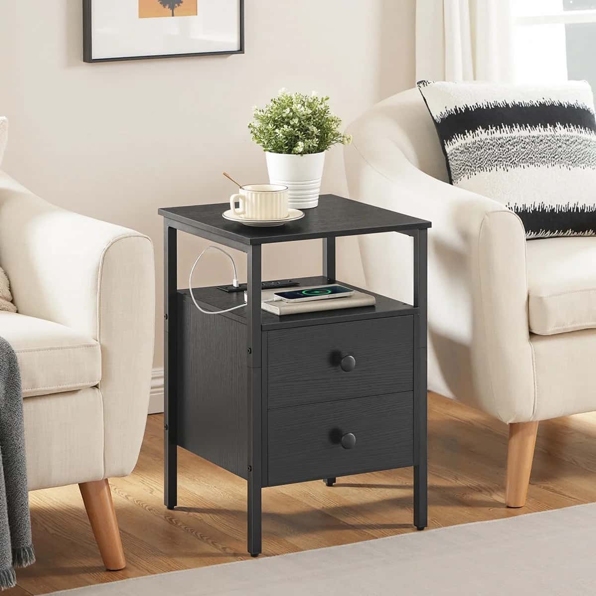 Black side table with a plant and cup in a living room setting