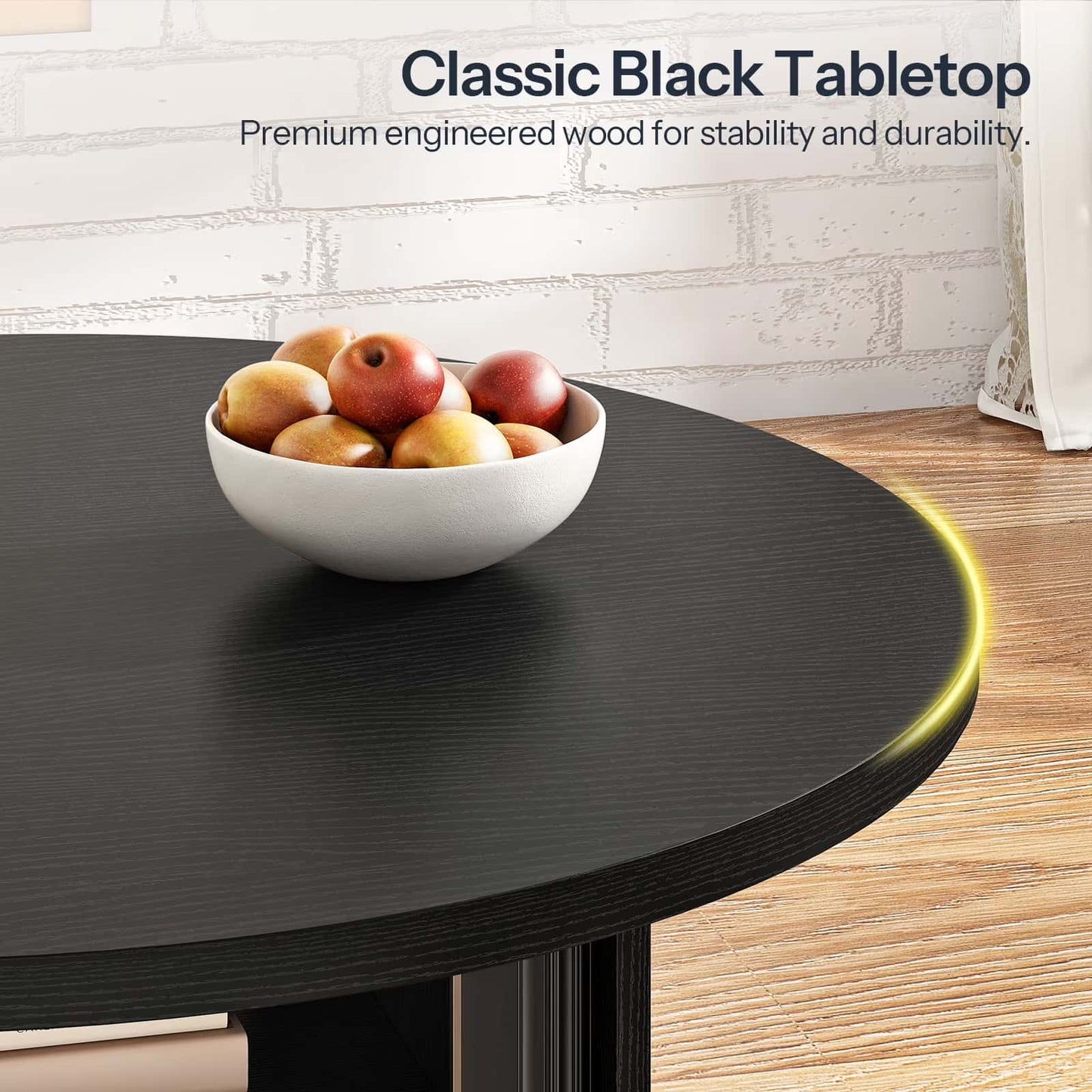 Round black table with a bowl of apples on a light wood floor.