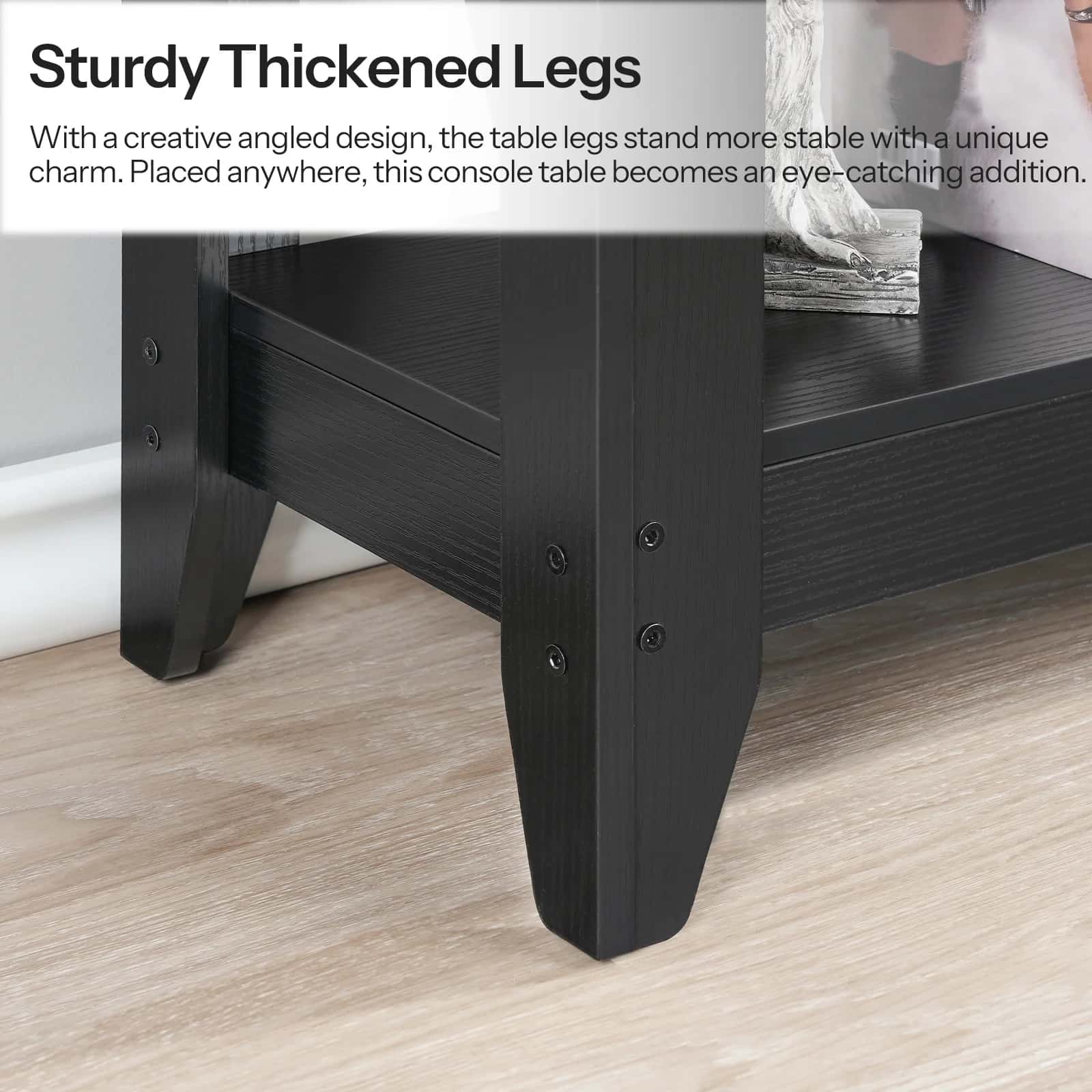 Black console table with sturdy thickened legs on a wooden floor, text describing design features.