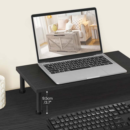 Laptop on a black stand with a keyboard on a desk, showing a living room scene on screen.