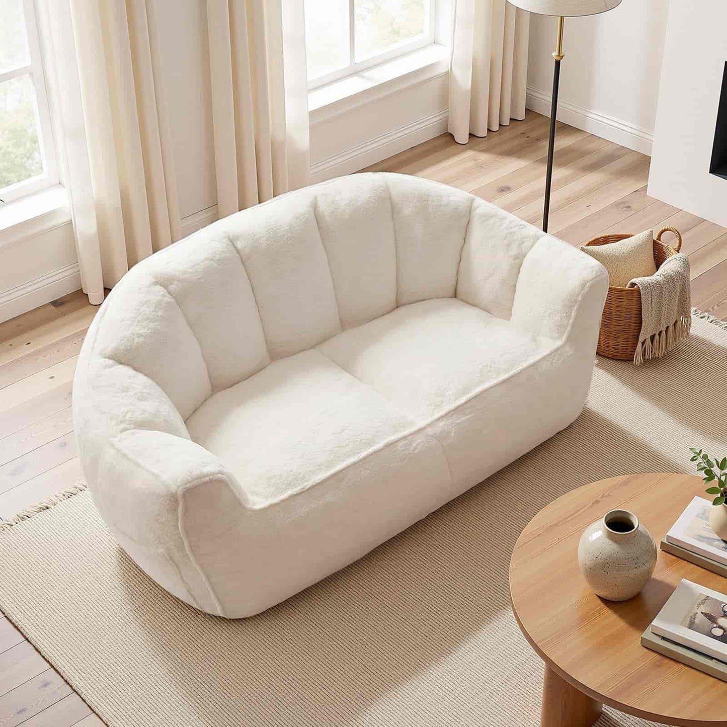 White plush sofa in a living room with wooden floor and window.