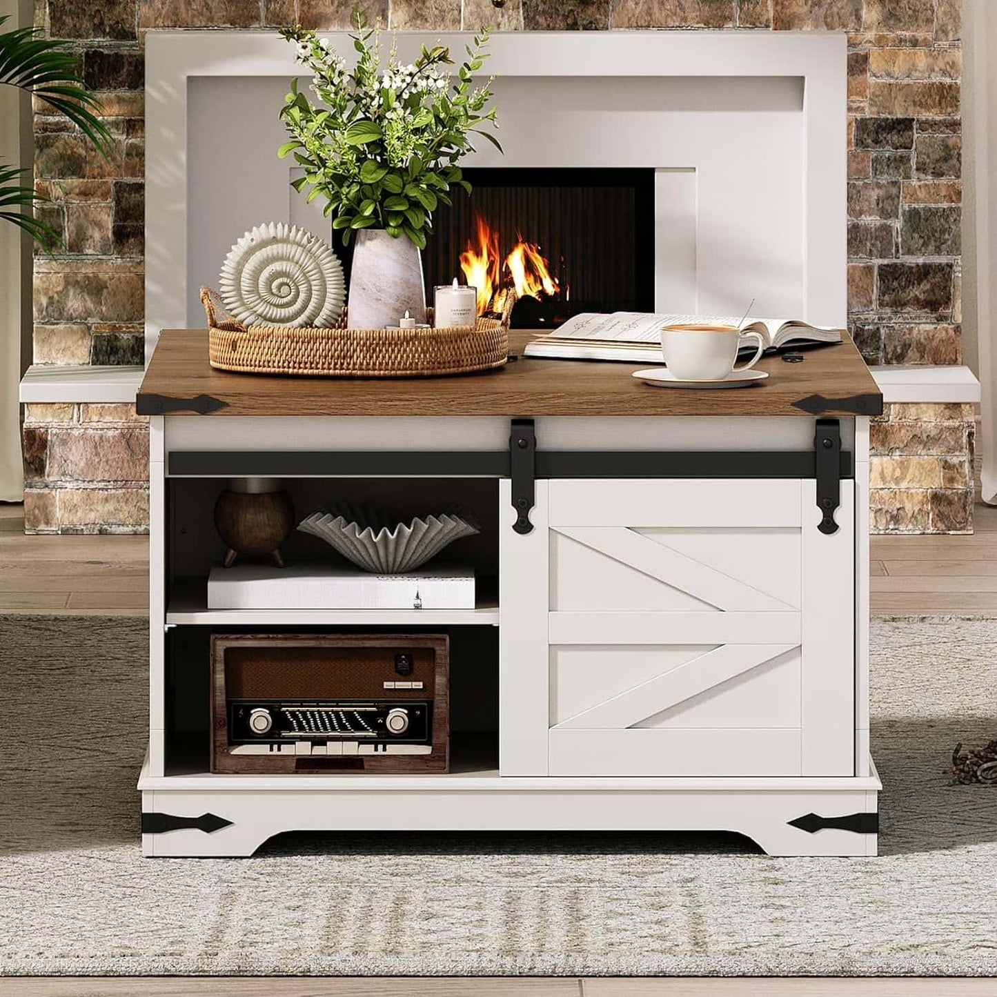 White entertainment console with wooden top against a stone wall.