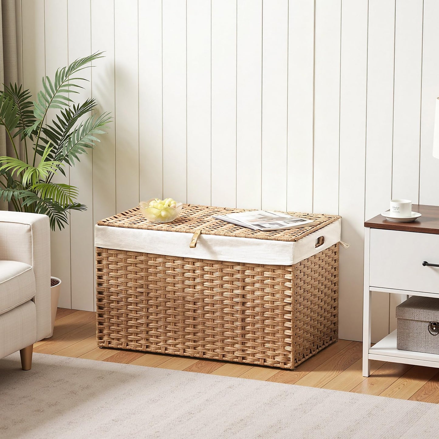 Wicker storage basket with a white liner in a room with a plant and furniture.