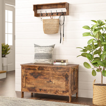 Wooden coat rack with hooks above a wooden bench in a room with plants and a pillow.