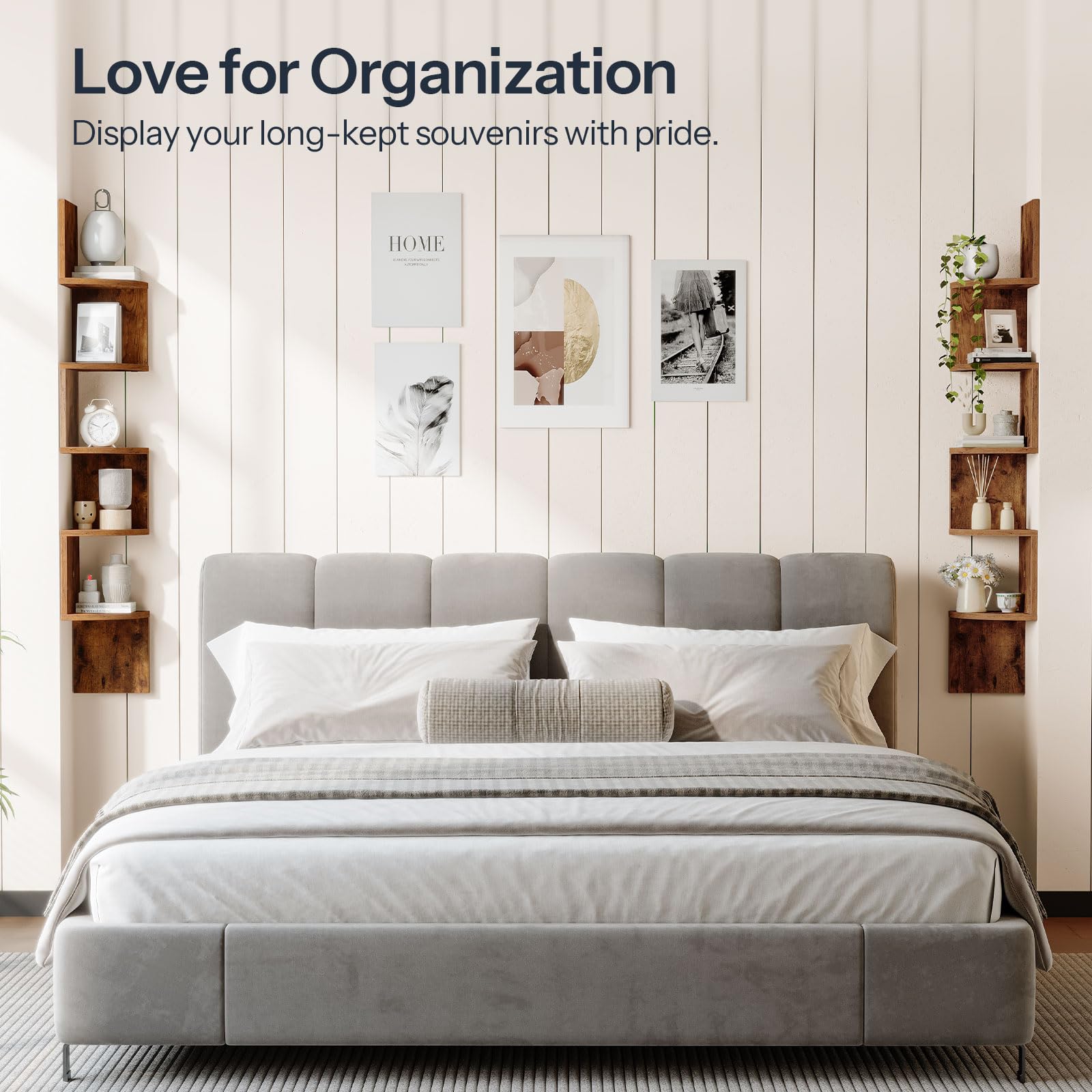Gray upholstered bed with white bedding in a room with wooden shelves and framed pictures on the wall.