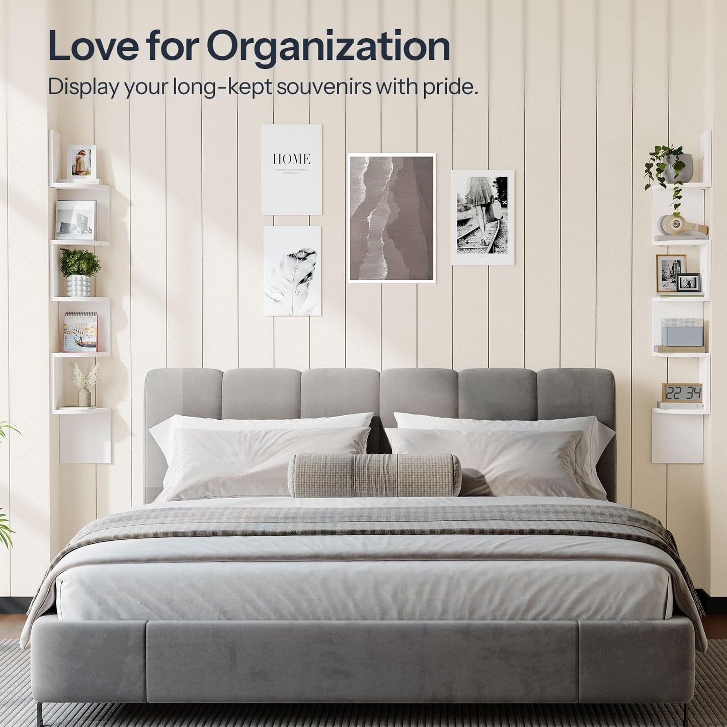 Gray upholstered bed with white bedding in a room with shelves and framed pictures on the wall.
