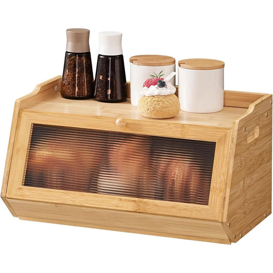 A bamboo kitchen bread box with a glass window showing sliced bread inside, topped with two spice bottles, two white canisters with bamboo lids, and a small decorative pastry, on a white background.