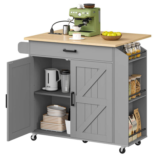 Gray rolling kitchen cart with a light wood top, featuring a drawer, barn-style door, open shelf with dishes, side storage shelves with jars and bags, and caster wheels. The cart is shown on a white background with kitchen props including an espresso machine, cups, lemons, and storage containers.