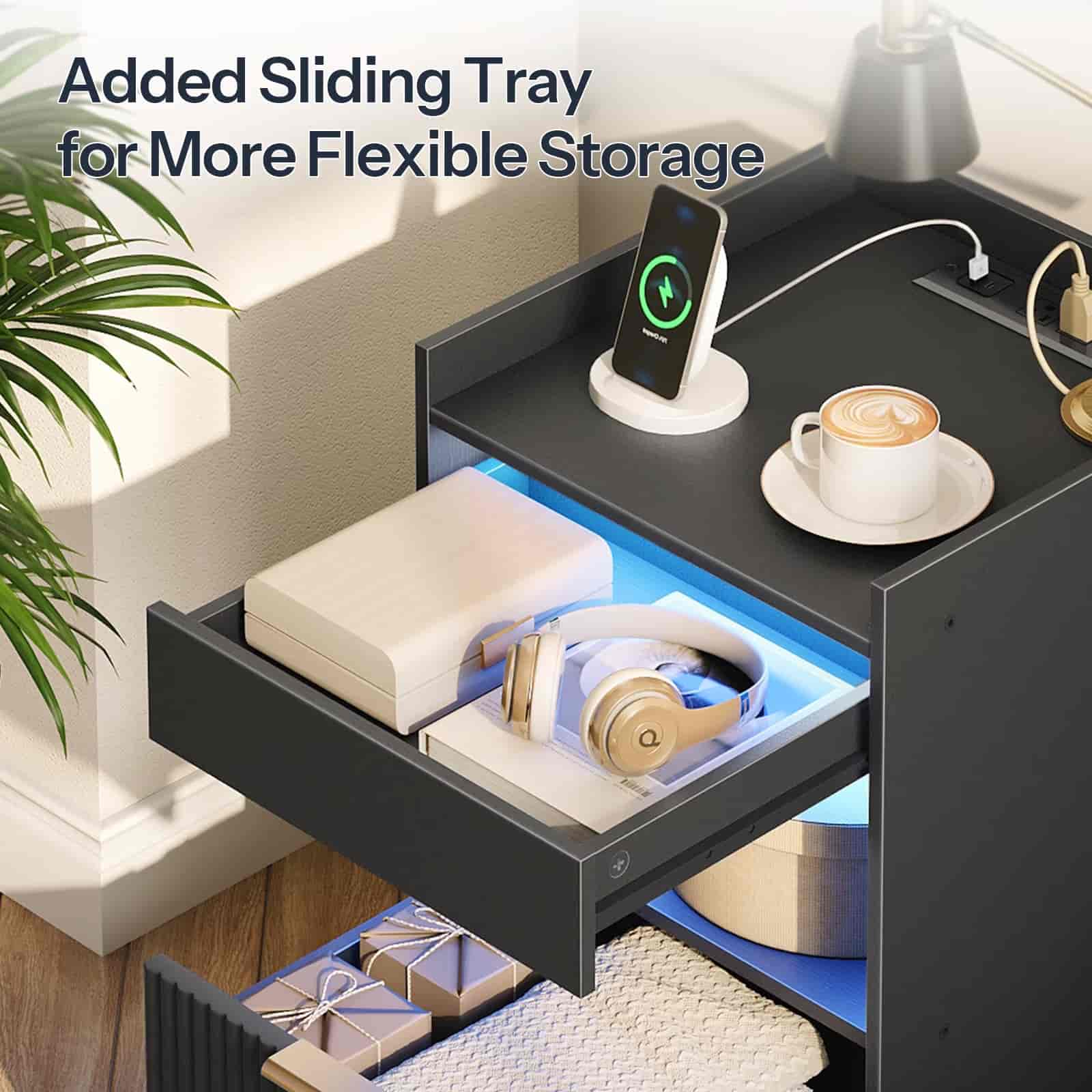 Nightstand with added sliding tray for flexible storage, featuring a phone, coffee cup, and other items.
