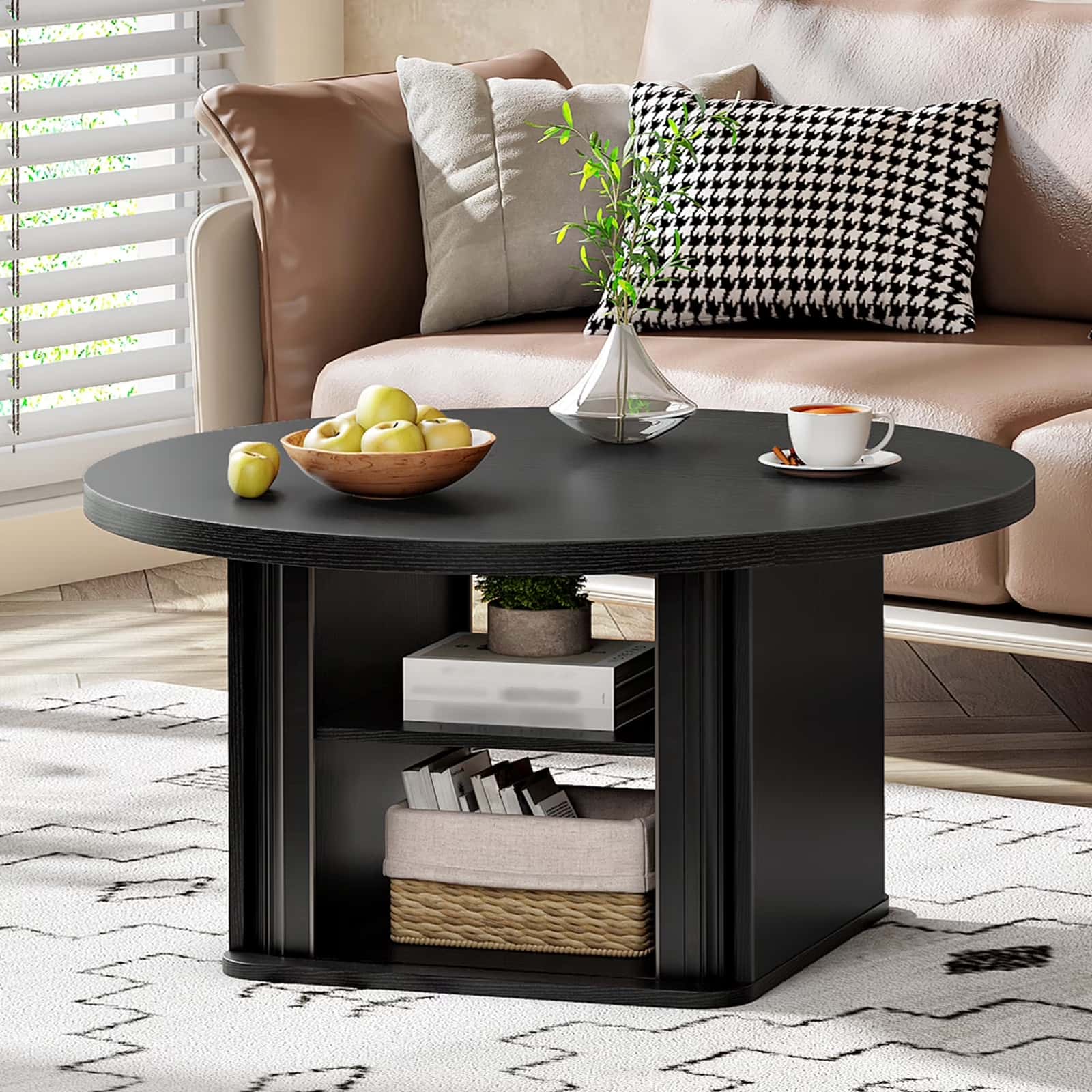 Black circle coffee table with open storage cubby holding magazines and boxes in front of a sofa.