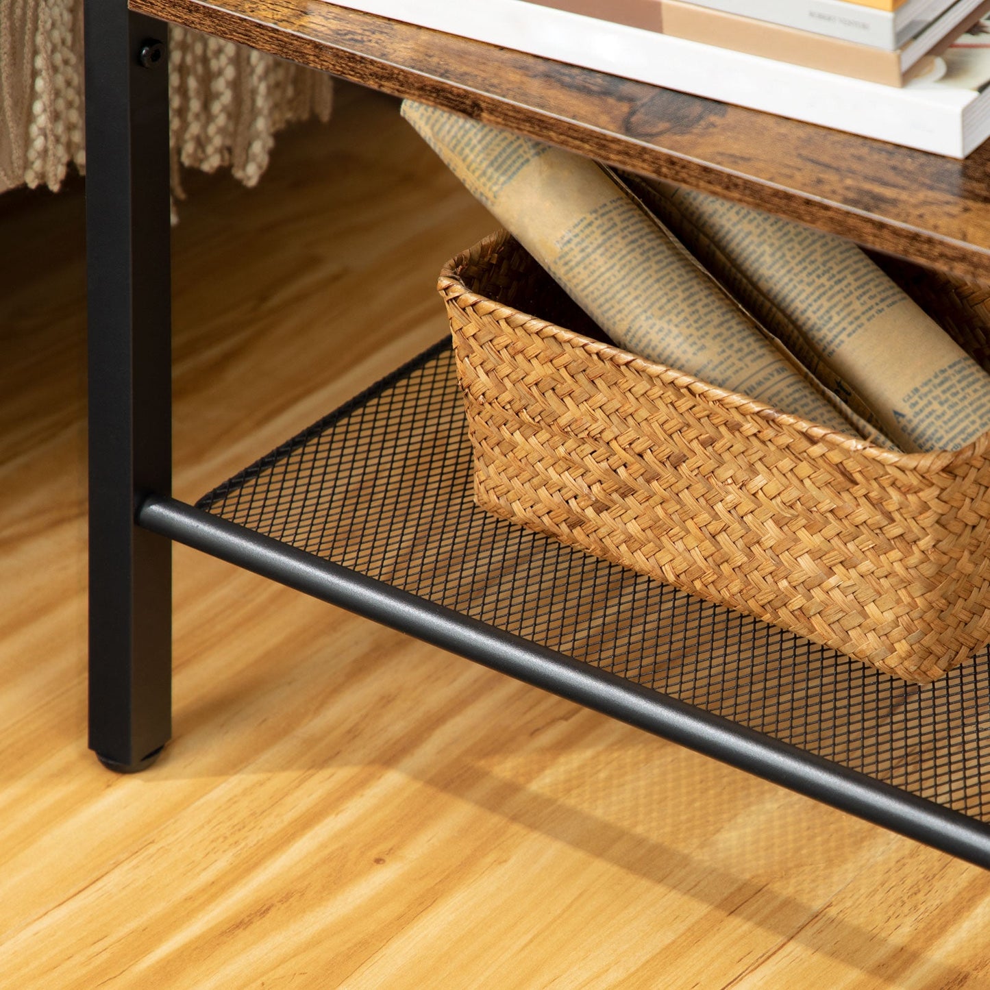 Bottom metal mesh shelf of the end table holding a woven storage basket for magazines.