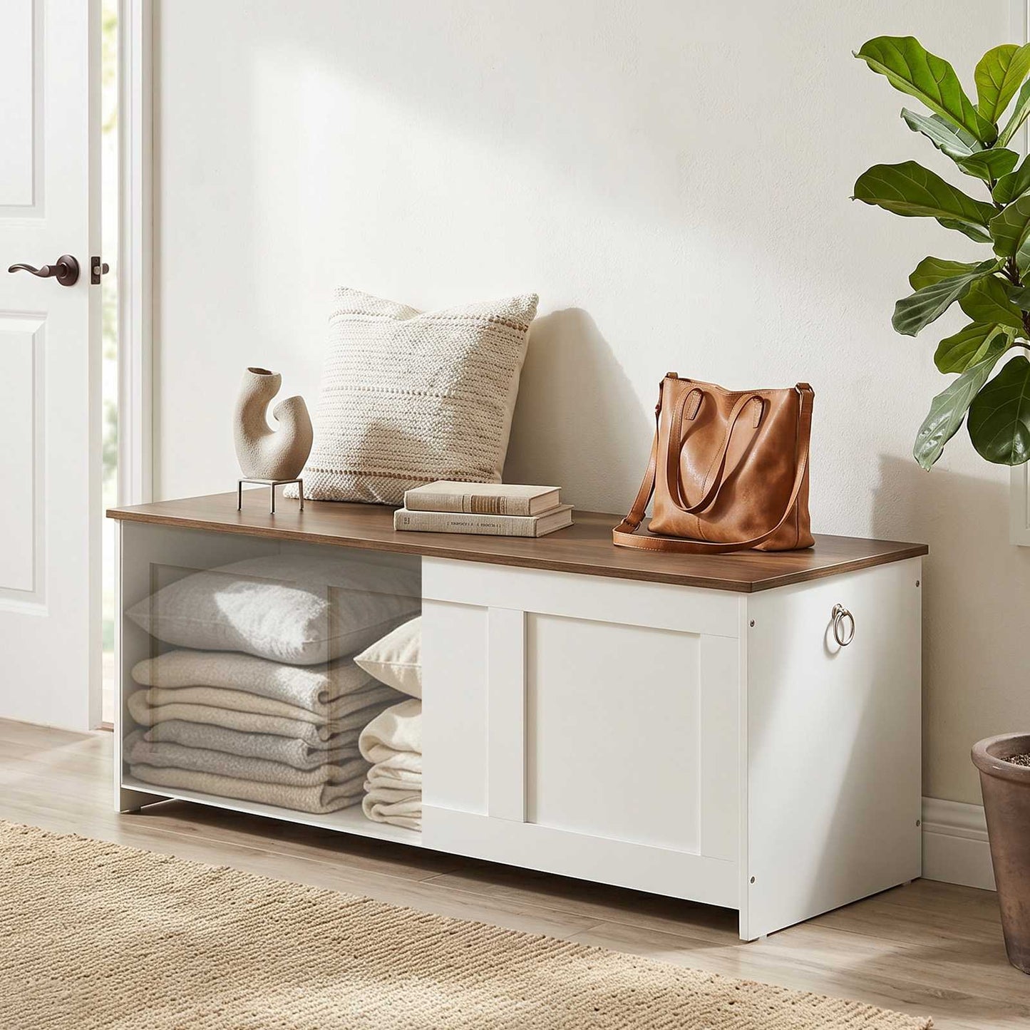 White entryway shoe storage bench styled with a leather handbag, keys, and an open cabinet shelf displaying folded blankets underneath.