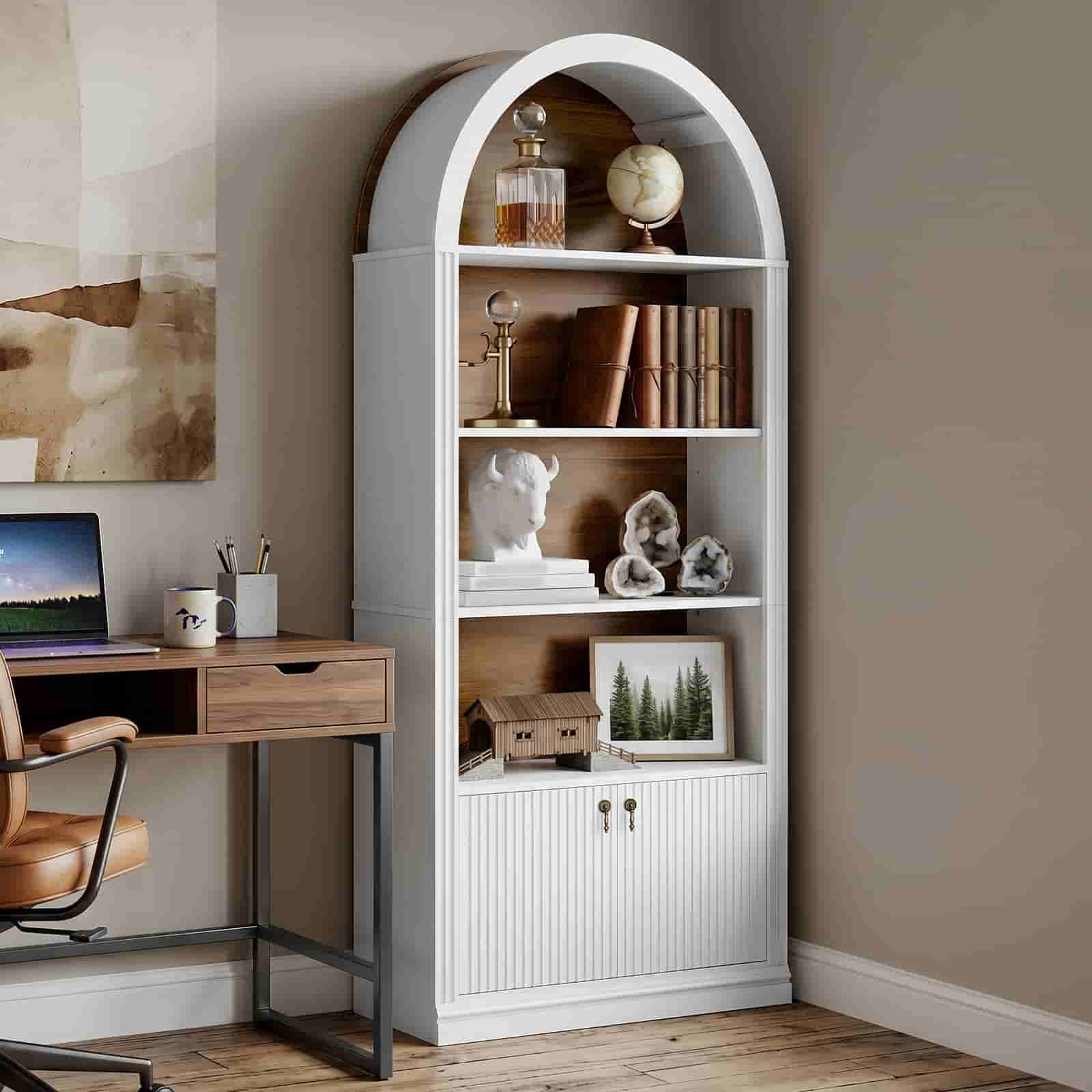 White arched hutch bookcase styled with books and art pieces next to a rustic wooden desk in a home office.