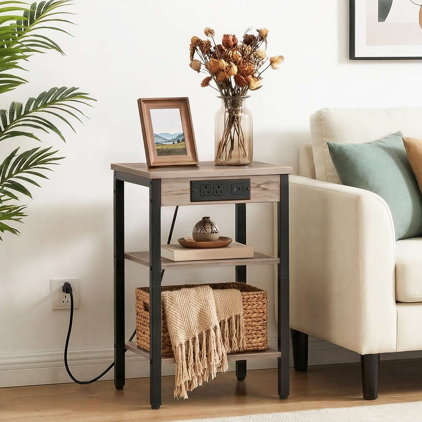 Industrial greige end table styled next to a living room sofa holding decor accents and a basket.