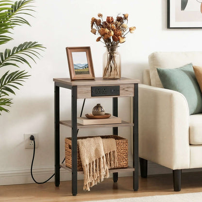 Industrial greige end table styled next to a living room sofa holding decor accents and a basket.
