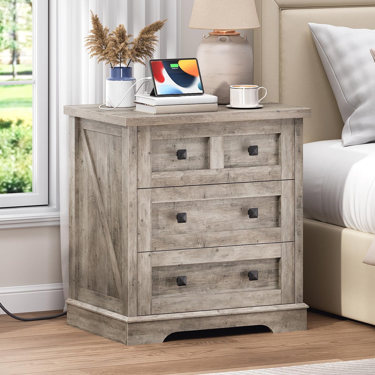HOOBRO farmhouse greige nightstand with a hidden charging station standing next to a bed holding a tablet.