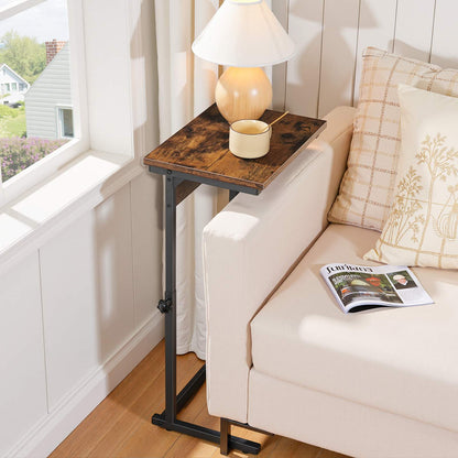 Industrial C-shaped side table styled in a cozy living room next to a fabric sofa with a table lamp.